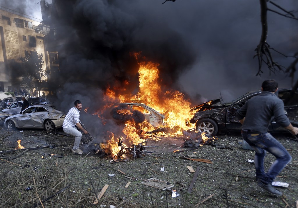 Lebanese men run to remove dead bodies from burned cars, at the scene where two explosions have struck near the Iranian Embassy killing several, in Beirut, Lebanon, Tuesday Nov. 19, 2013. The blasts in south Beirut’s neighborhood of Janah also caused extensive damage on the nearby buildings and the Iranian mission. The area is a stronghold of the militant Hezbollah group, which is a main ally of Syrian President Bashar Assad in the civil war next door. It’s not clear if the blasts are related to Syria’s civil war.