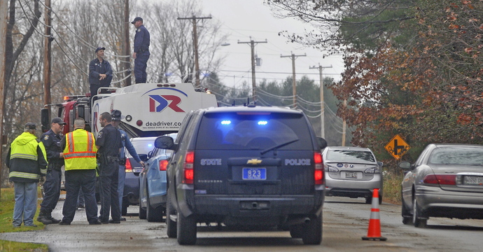 Shawn Mullen, 46, a delivery driver for Dead River Oil, stands to the left of a state police investigator on the top of the oil truck after a fuel spill on Belgrade Road in Oakland on Friday.