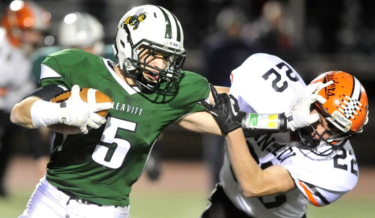 Staff photo by Michael G. Seamans CLASS C FOOTBALL:Leavitt High School running back Nate Coombs, 5, stiff arms Winslow High School's Nathan Amand, 22, in the second quarter in the Class C state championship game at Fitzpatrick Stadium in Portland on Saturday. Leavitt defeated Winslow 47-18.