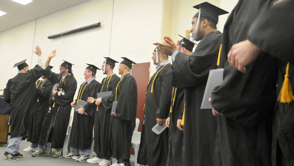 HERE COMES THE GRADs: Maine State Prison inmates congratulate each other Monday after receiving diplomas at the Warren prison from the University of Maine at Augusta.