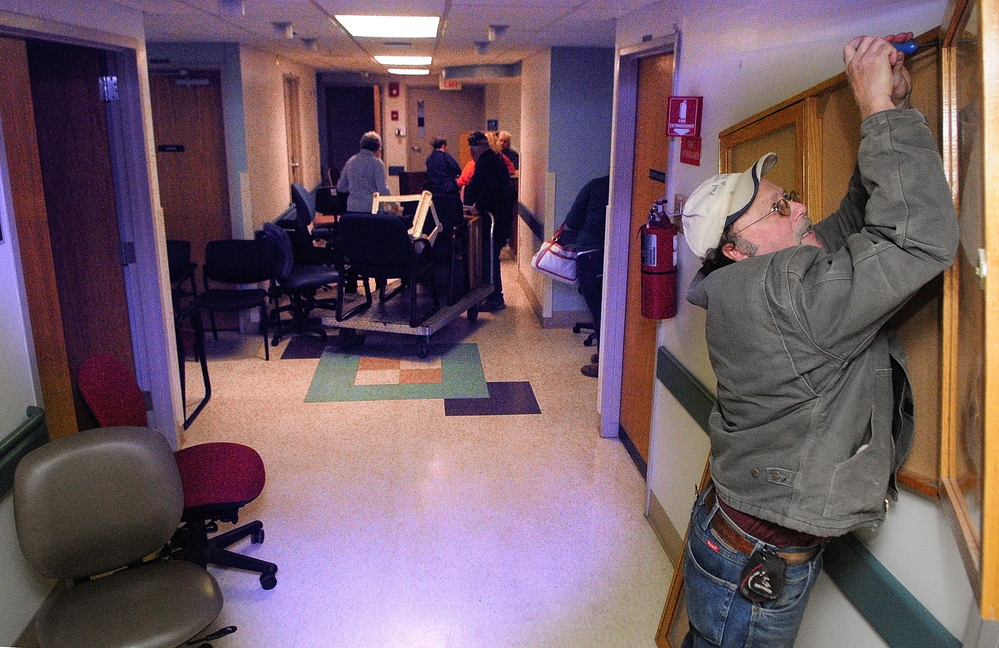 Everything must go: Paul Marcotte unscrews a display case from the wall during the public sale of items from the former MaineGeneral Medical Center on Saturday on East Chestnut Street in Augusta.