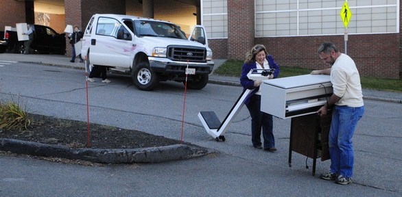 Sale: Deb Poulin, left, reacts as the rolling cabinet Lou Berthell is pushing almost tips over as it catches on a crack in pavement outside the public sale of items from the former MaineGeneral Medical Center on Saturday on East Chestnut Street in Augusta. Berthell said he was buying the scale and cupboards for his business Power Play Personal Training in Hallowell.