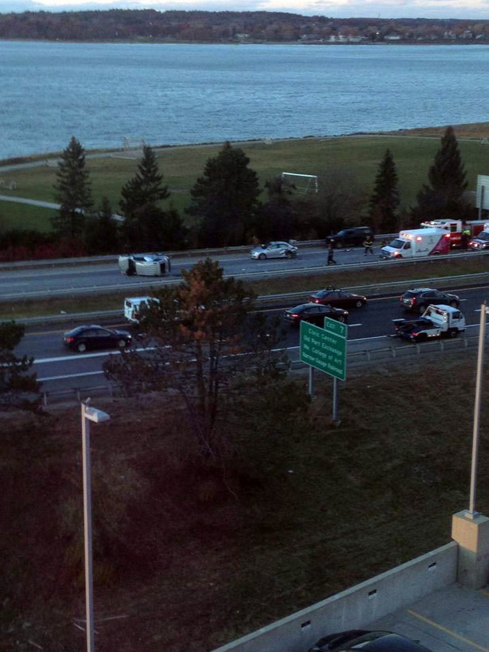 An overturned vehicle lies in the center of Interstate 295 southbound in Portland, trailed by another damaged vehicle and an ambulance.