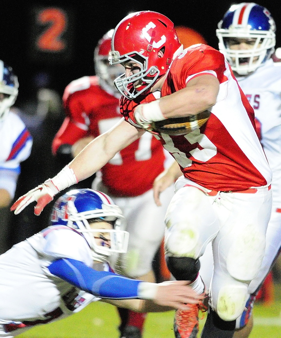 Staff photo by Joe Phelan Cony running back Reid Shostak, right, avoids a diving tackle by Messalonskee defensive back Jake Dexter during a game on November 8, 2013 at Alumni Field in Augusta.