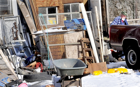 FOOD SOURCE: Bill Mitchell leaves a barn Wednesday on his Smithfield farm after working around boxes and buckets of food that are stored in the building and fed to his pigs.