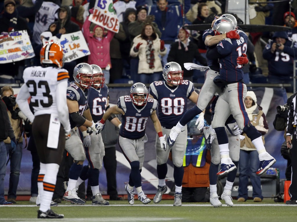 New England Patriots quarterback Tom Brady (12) celebrates his go-ahead touchdown pass to wide receiver Danny Amendola (80) with Julian Edelman, hugging Brady, in the fourth quarter of an NFL football game against the Cleveland Browns, Sunday, Dec. 8, 2013, in Foxborough, Mass. The Patriots came from behind to win 27-26.