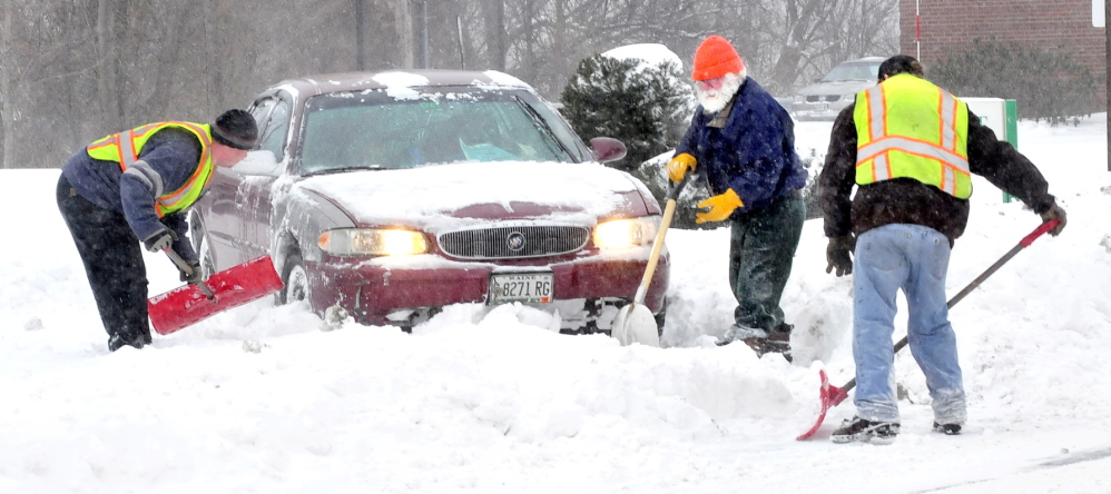 Staff photo by David Leaming SANTAS HELPERS: Looking alot like the image of Santa Claus with white hair, beard and a red face, William Saucier, center, got some help digging his car after it got stuck in snow in Waterville on Sunday. Waterville Public Works employees Larry Colson, left, and Brian Ames pitched in to dig the car out.