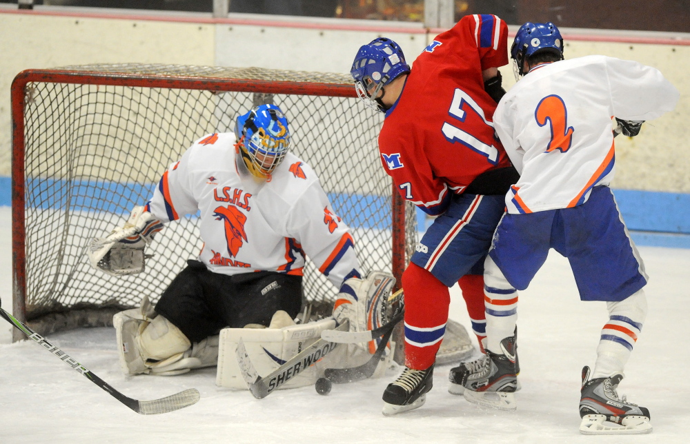 Lawrence/Skowegan goalie Sam Edmondson, 27, makes a save as Messalonskee High School’s Dan Condon, 17, fights for the rebound with Lawrence/Skowhegan’s Andrew Carpenter, 2, in the first period at Sukee Arena in Winslow on Wednesday.