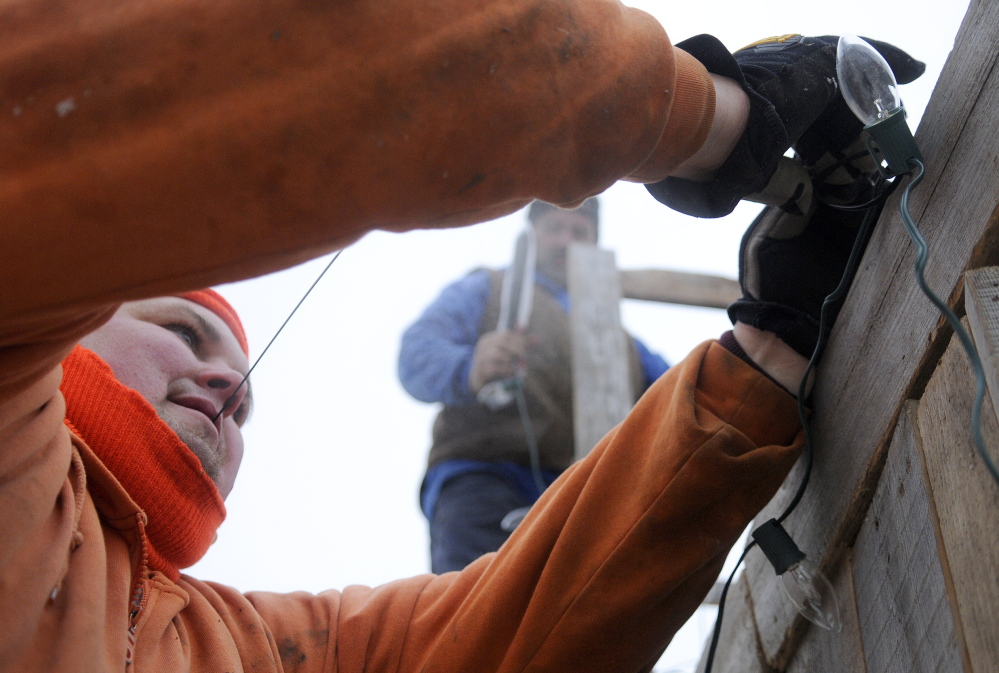 AWAY IN A MANGER: EJ Perry Construction employees Scott Gress, left, and John Kinnie set lights on a manger they built Friday on Water Street in Hallowell. The First Baptist Church of Hallowell will present a live nativity scene Christmas Eve at the creche, which was built with labor donated by Perry Construction of Hallowell.