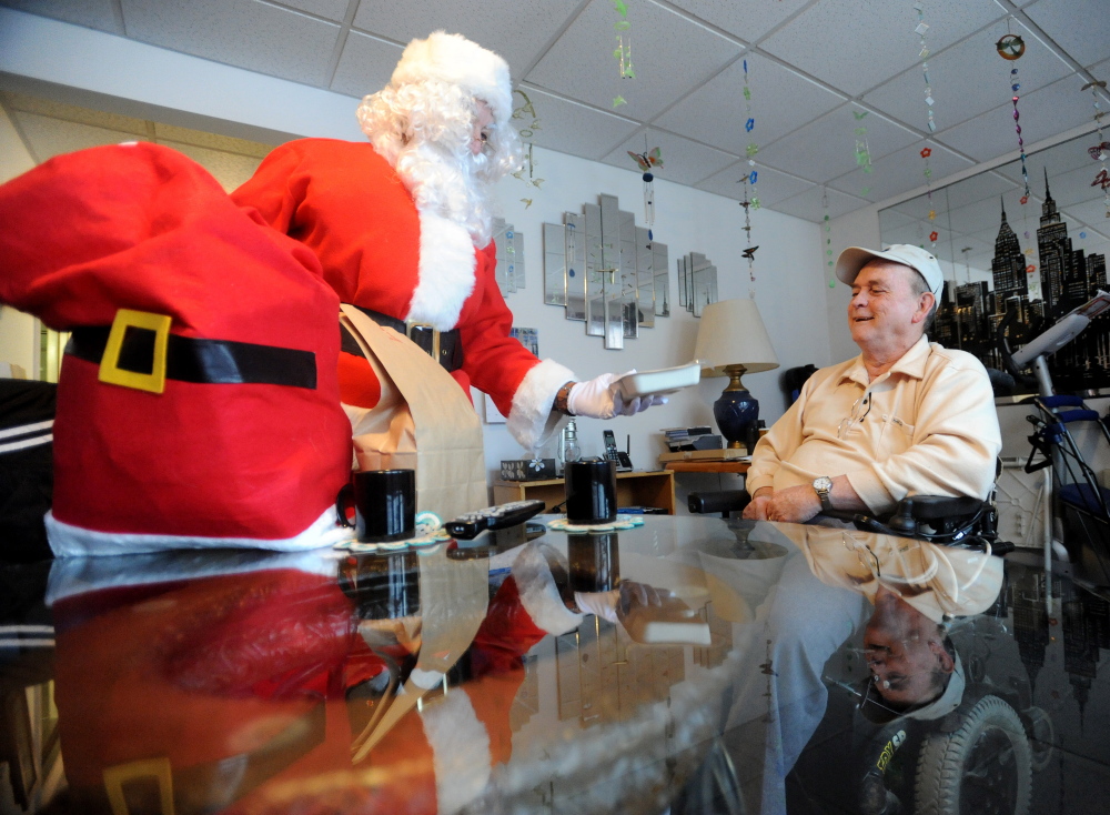 Staff photo by Michael G. Seamans SPECIAL DELIVERY: Romeo Remy, 69, gets a special Meals-on-Wheels delivery at his apartment at Elm Towers in Waterville from Santa Claus on Tuesday, Dec. 24, 2013.