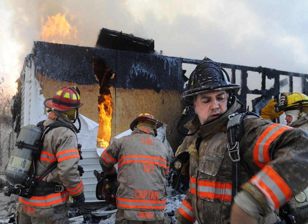 Staff photo by Andy Molloy FLAMES: Firefighters take cover from smoke and flames Wednesday while battling a fire on the Plains Road in Litchfield. Dozens of volunteer firefighters from area communities responded to the blaze that injured one man, destroyed a garage and heavily damaged the attached home.