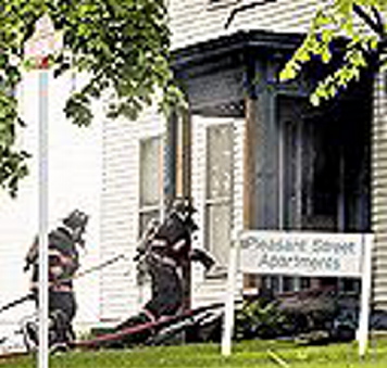 CHECKING IT OUT: In this May file photo, firefighters walk into an apartment building at 26 Pleasant St. to check for remaining hot spots. Earlier this month, landlord Ryan Chamberland pleaded guilty to misdemeanor criminal charges related to the fire, but those charges will be dismissed if he fixes deficiencies.