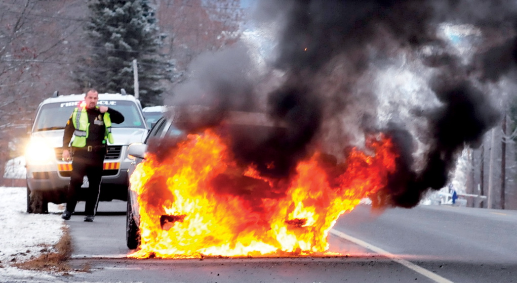 Fairfield Police Sgt. Paul St. Amand monitors a car that burst into flames on Norridgewock Road on Tuesday. Driver Margaret Genest said at the scene that the car was not accelerating normally and she pulled off the side of the road. A moment later she said she saw smoke followed by fire coming from under hood. “That’s when I decided to get out,” said Genest, of Fairfield. The car was extinguished and traffic resumed. There were no injuries, according to St. Amand.