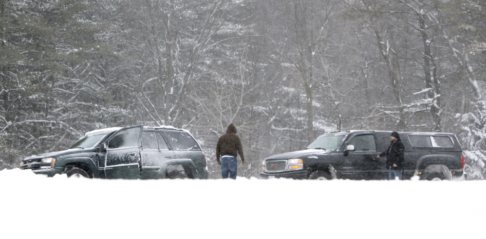Gregory Rec/Staff Photographer A motorist in a truck stops to help a driver who got stuck in a snowbank in the southbound lane of the Maine Turnpike in Arundel on Friday.