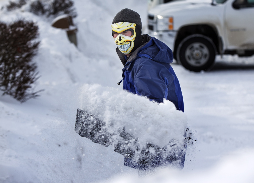 With the temperature at 3 degrees, Drue Ford shovels snow wearing a face mask to guard against frostbite Friday in Brunswick.
