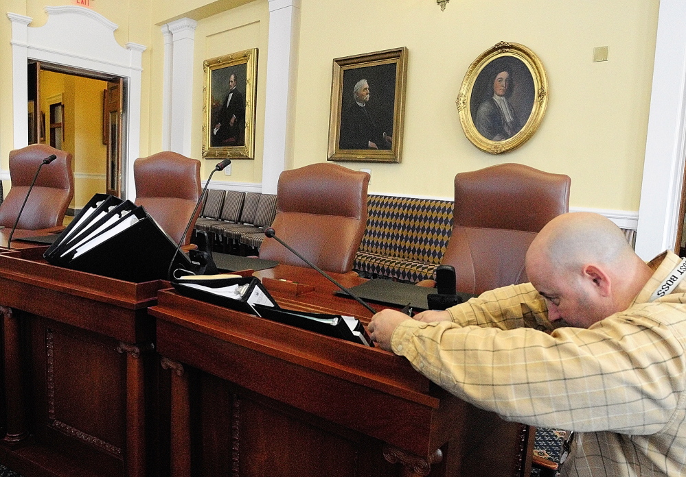 Nik Rende, a senior programmer/analyst for the Maine Legislature, fixes a microphone in the Senate Chamber of the State House in Augusta. He and other workers were preparing for the new session that opens Wednesday morning.