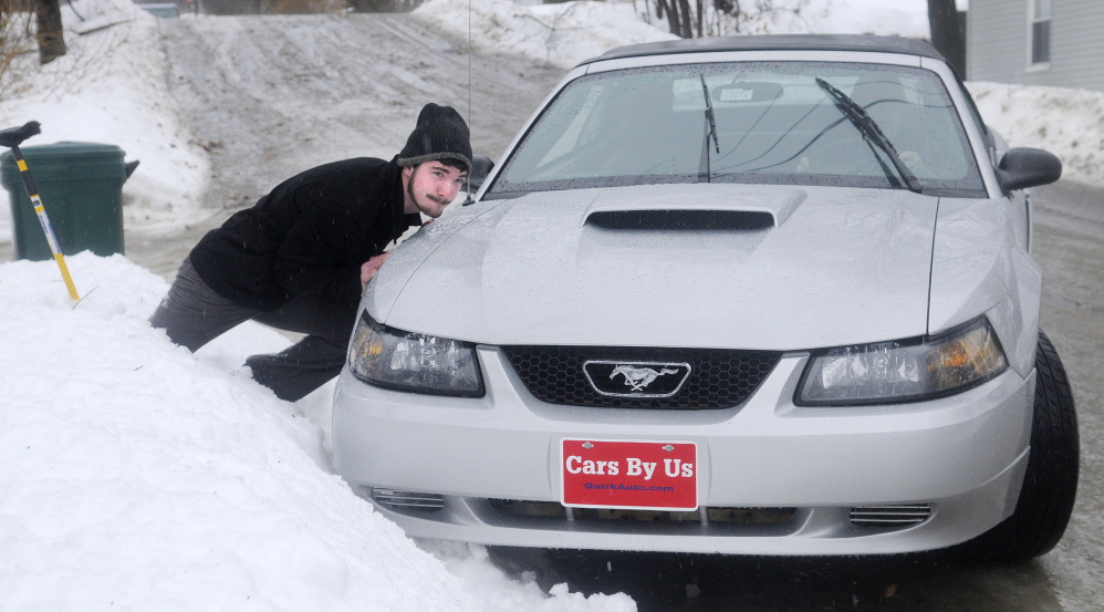 ELEMENTS: Michael Johnston attempts to push John Thiele’s car out of a snow bank Monday in Hallowell. Drivers encountered hazardous conditions across Maine while heavy rain fell on already slick roads.