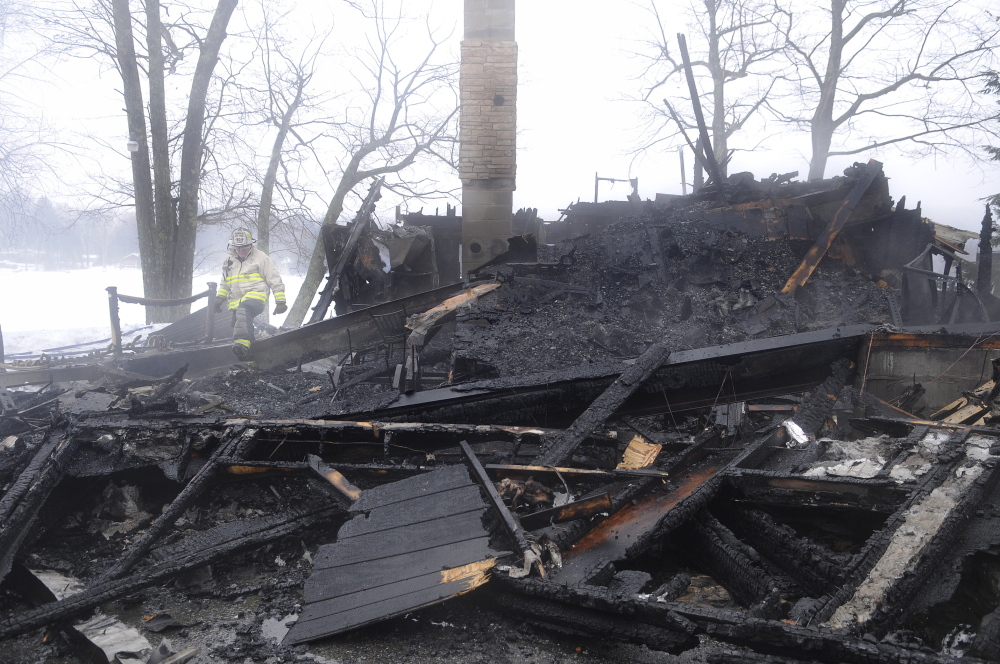 REMNANTS: Assistant Monmouth Fire Chief Ed Pollard searches for hot spots in the remnants of a camp that burned Monday morning in Monmouth.
