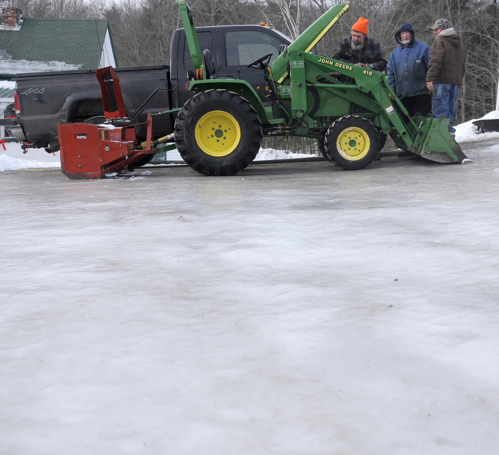 FIRM: Steve Lord, left; his father, Freeman; and brother Delmont replace an electric cable Tuesday in a tractor at the elder Lord’s farmhouse in Hallowell. The men were fixing the tractor, which they use to blow snow, while ice covered the farmyard after Monday’s rainstorm.