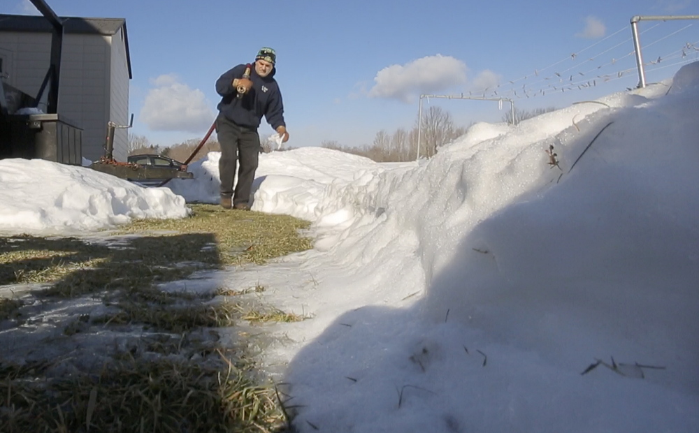 Jim Carroll walks a hose behind a house in Limerick while delivering oil Tuesday. His family-owned business has four trucks to serve its roughly 3,500 customers in western York County and in New Hampshire.