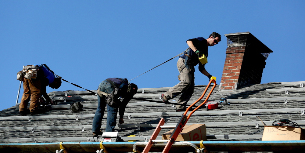 Matt Bush, Seth Kiernan and Brandon Bernard of ReVision Energy install support systems for solar panels on a house on Falmouth Road in Falmouth.