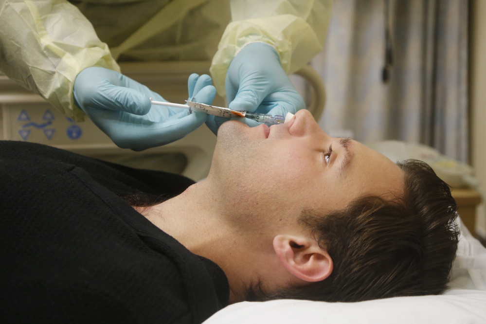 Daniel Bennett, 26, of College Park, Md., has live flu virus sprayed into his nose as part of a study at the National Institutes of Health in Bethesda, Md.