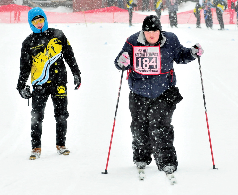 THE RACE IS ON: Caitlin Killarney of Families Matter Inc. in Waterville competes in the 100-meter nordic race during the 45th annual Special Olympics Maine Winter Games at Sugarloaf USA on Monday, Jan. 27, 2014. At left, Colby Watts of Maranacook High School cheers her on.