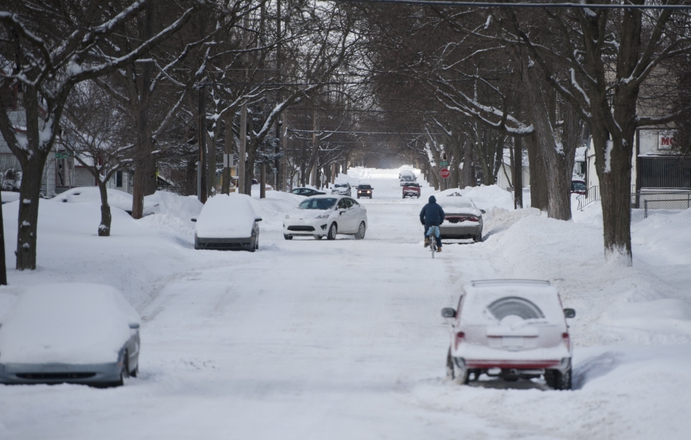 A lone bicyclist makes his way down a snow covered street onon the northeast side Jackson, Mich., on Monday, Jan. 27, 2014. Gusting winds and blowing snow caused whiteout conditions Monday that made travel treacherous on some Michigan roadways, and hundreds of schools closed because of the severe weather.
