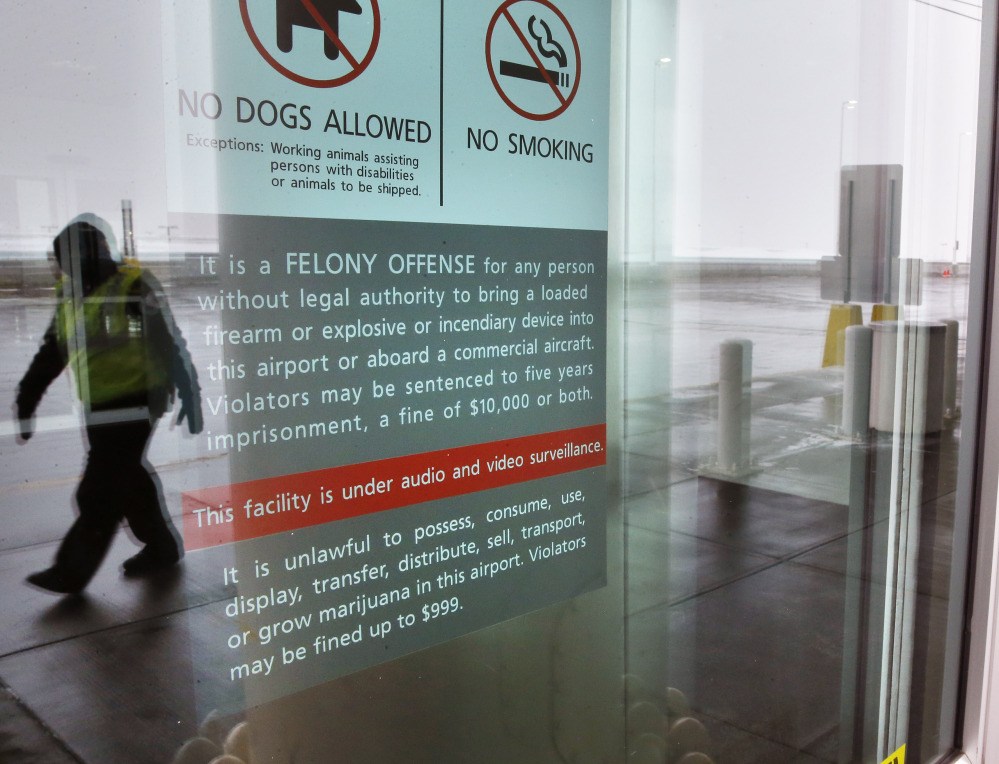 A security officer walks near a notice prohibiting marijuana possession at Denver International Airport.