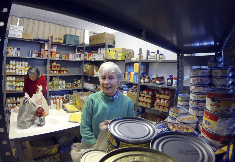Food pantry: Volunteers Elaine Brann, left, and Jeanne Rocque pack groceries for a client on Thursday at the Augusta Food Bank at St. Mark’s Episcopal Church in Augusta.
