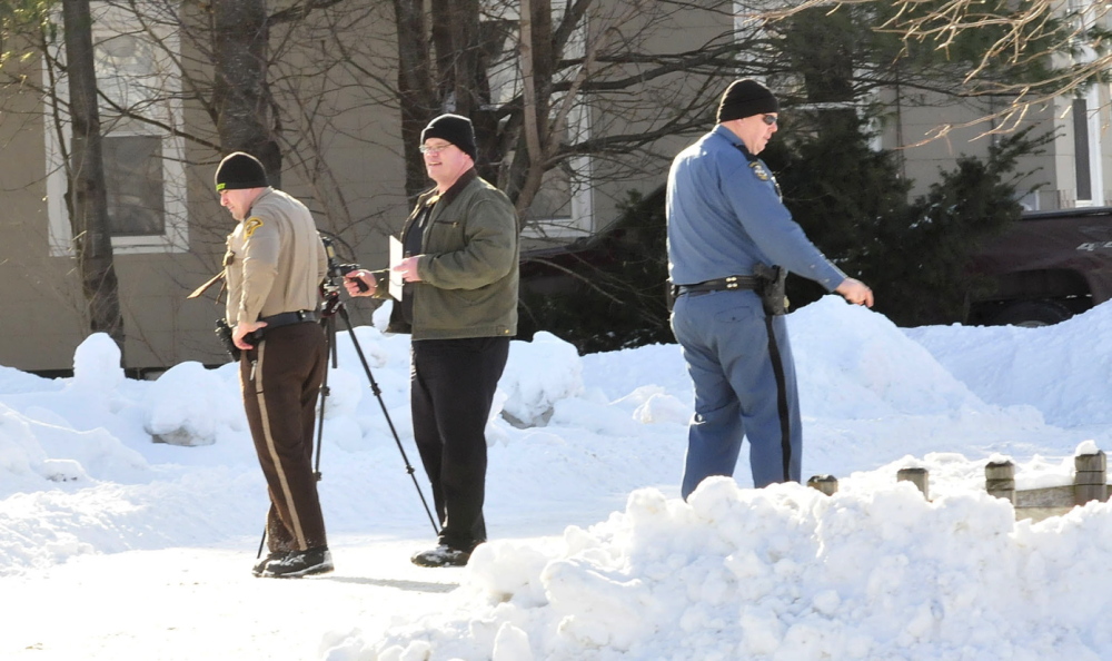 CLUES: Police officers use equipment to survey and record data on Lander Street next to the Skowhegan Savings branch in Bingham after it was robbed Tuesday.