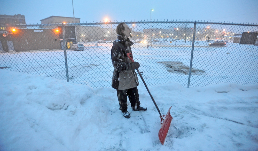 Staff photo by Michael G. Seamans STAYING AHEAD: Thomas Beeney takes a break after clearing the walkways at the Waterville Public Library as snow falls on Thursday. The winter storm is expecting to deposit at least one foot of fresh powder before moving out this afternoon.