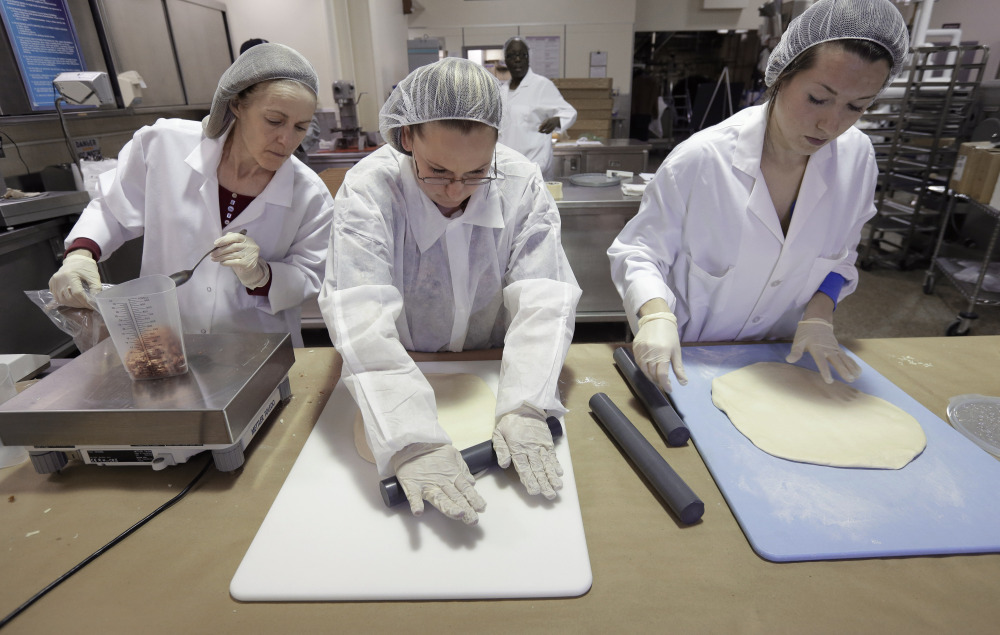 Food researchers Mary Scerra, left, Priscilla Bitopoulos and Lauren Pecukonis prepare ingredients for prototype pizzas in a kitchen at the U.S. Army Natick Soldier Research, Development and Engineering Center, in Natick, Mass.