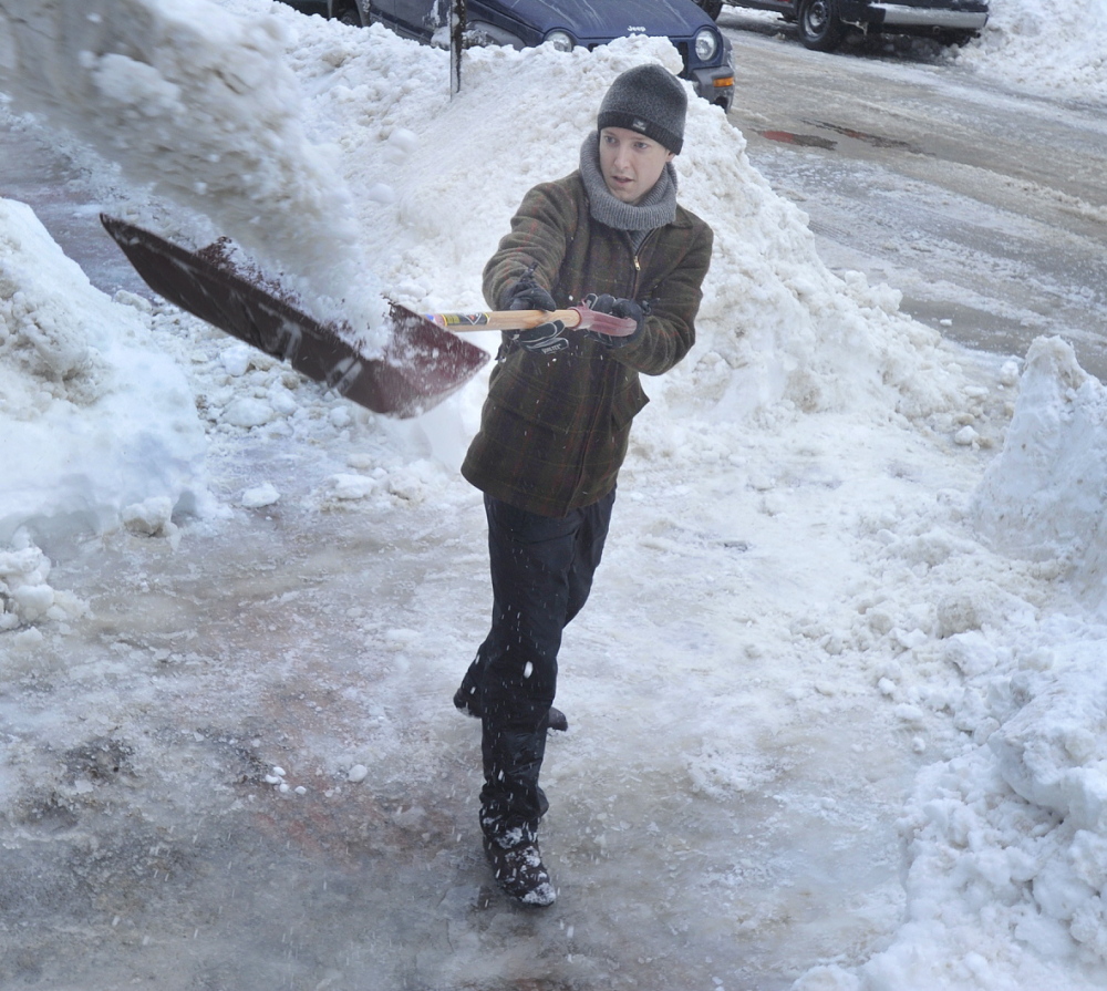 Levi Bridges heaves heavy,wet snow onto banks above his head Friday while clearing his driveway on Portland’s Vesper Street. Another storm Saturday could drop another half-foot.