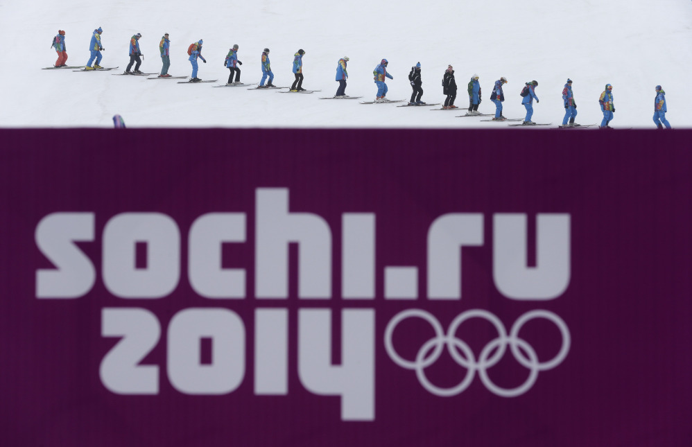 Volunteers ski down the slope after the men’s snowboard cross competition was cancelled due to fog at the Rosa Khutor Extreme Park Monday.