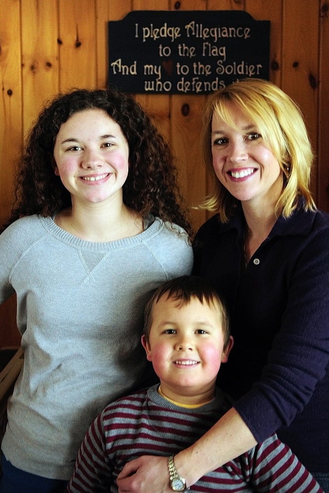 THE PLEDGE: Lynn Lewis, right, poses for a portrait with her children Kimberlee, 17, left, and Nate, 6, in front of a sign that reads, “I pledge allegiance to the flag, and my heart to the soldier who defends it” on Friday February 14, 2014, in Monmouth.