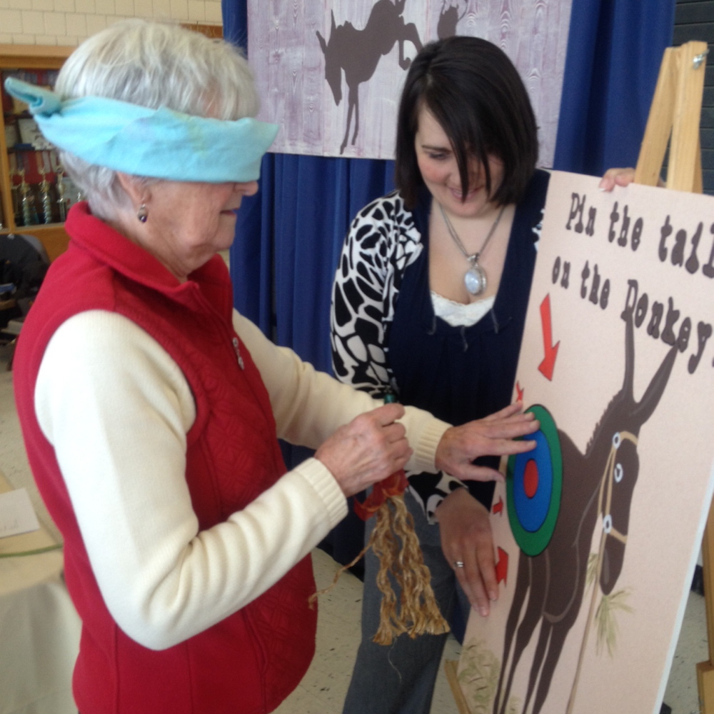 Fun at the Fair: Nancy Harrington, of Clinton, pins the tail on the donkey Saturday at Skowhegan’s annual FAB Fair while Katie Quinn, owner of Ass Over Teakettle Bloody Mary Mix officiates. The winner of the game received a jar of the spicy mix.