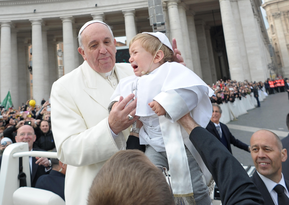 Nineteen-month-old Daniele De Sanctis, dressed up as a pope, is handed to Pope Francis as the pontiff is driven through the crowd during his weekly general audience in St. Peter’s Square at the Vatican on Wednesday.