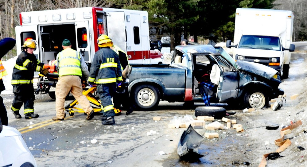 SERIOUS: Madison firefighters and ambulance personnel load one of two injured occupants of a pick-up truck that was hit by a delivery truck on Old County Road in Madison on Wednesday. Jon Bachelder, the driver of the delivery truck, said his shoelaces got tangled in his gas pedal and the truck went through a stop sign at the intersection, police said.