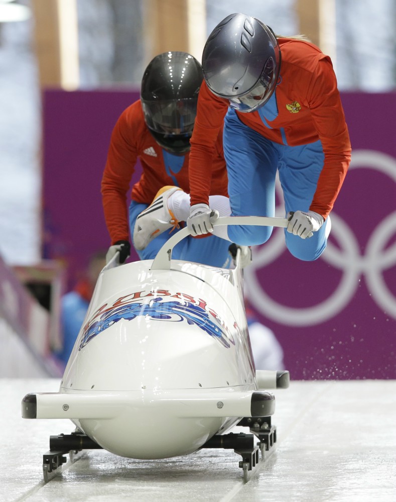 A track worker repairs some lights that were damaged after a worker was hit by a forerunner bobsled just before the men's two-man bobsled training at the 2014 Winter Olympics, Thursday, Feb. 13, 2014, in Krasnaya Polyana, Russia.