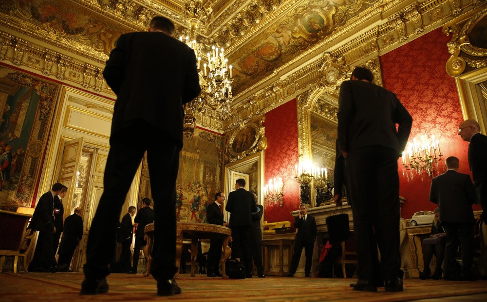 Delegation members wait outside the meeting room where foreign ministers, including Russian Foreign Minister Sergei Lavrov and Secretary of State John Kerry, were discussing the Ukraine crisis, Wednesday, March 5, 2014, at the Quai d’Orsay in Paris.