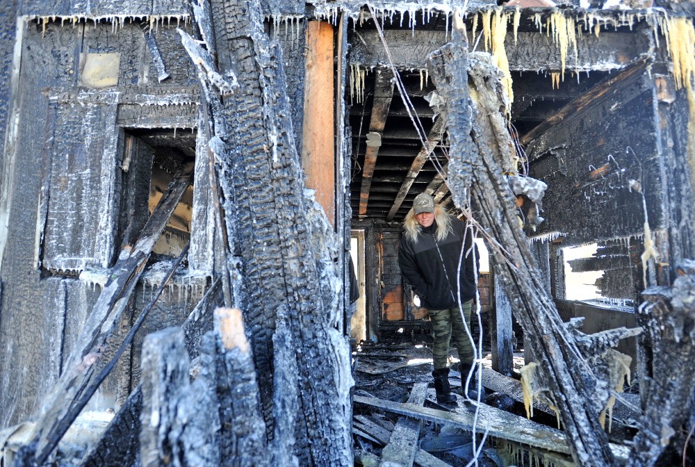 Farm FIRE: Aimey Ribeiro, 41, looks through her farm on Tupper Road in East Madison on Friday. The fire was reported around 9:30 p.m. on Thursday and destroyed the barn and most of the home and killed several animals.
