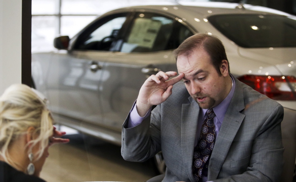 Morgan Moore, right, has a law degree and $80,000 in debt but works as a salesperson at a car dealership in Golden Valley, Minn. Shown here talking with a customer, Moore says the bearish jobs market has resulted in “a lost three or four years” for his generation.