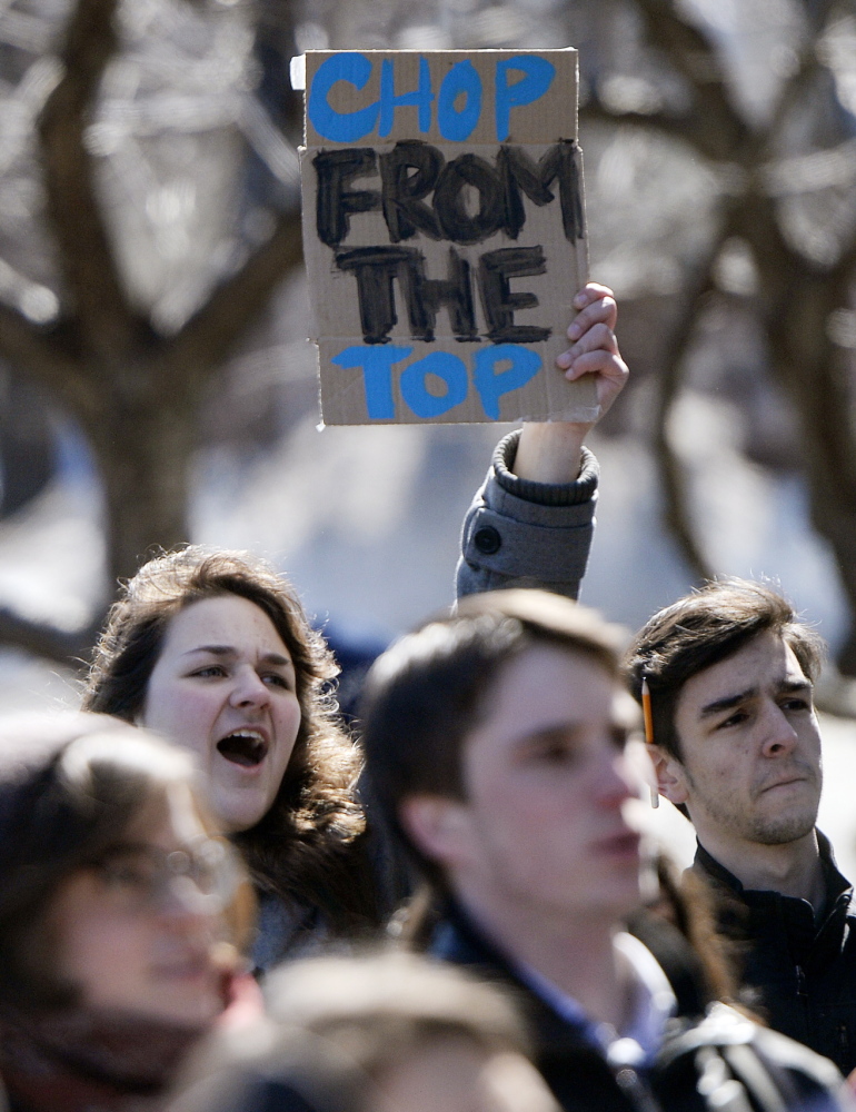 Rhiannon Vonder Haar, a sophomore at the University of Southern Maine, shouts while holding a sign that says “chop from the top” as students and faculty protest cuts at the university on Monday.