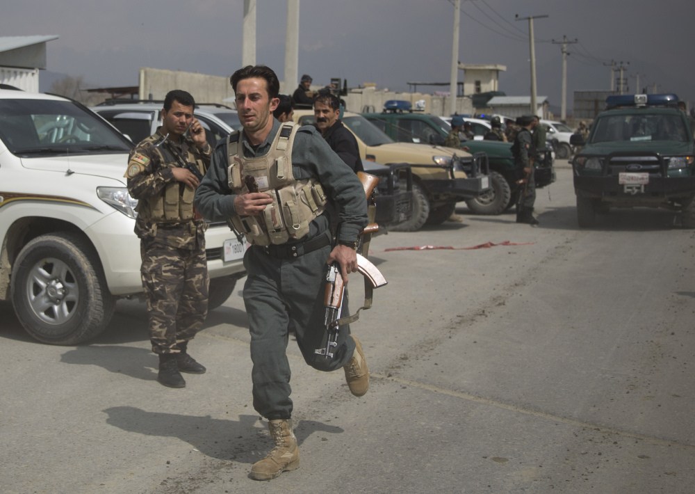 An Afghan police man rushes to the scene as Taliban militants attacked the main Afghan election commission’s headquarters in the outskirts of Kabul, Afghanistan, firing on the compound with rocket-propelled grenades and heavy machine guns from a house outside its perimeter wall on Saturday.