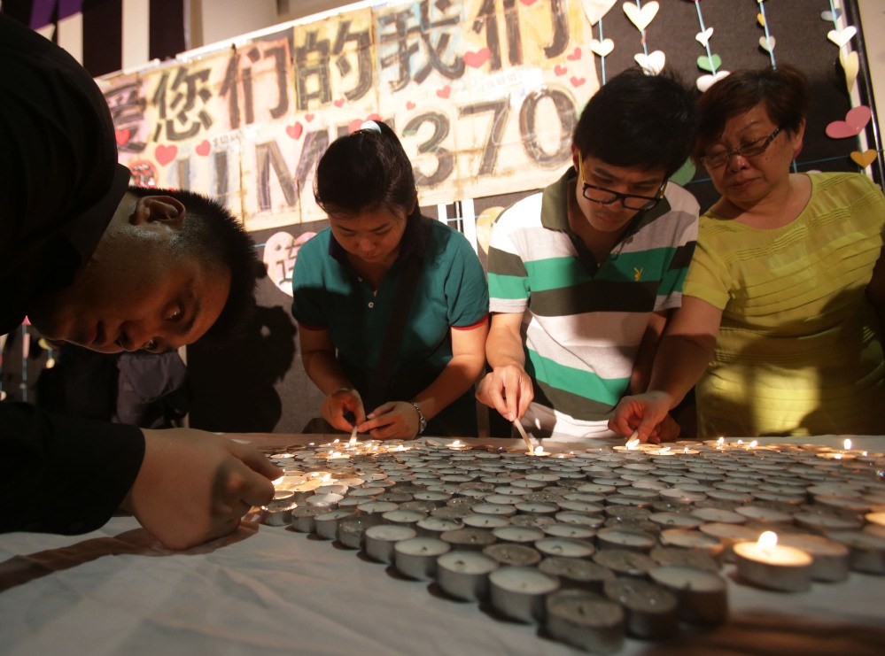 People light candles during a ceremony for the passengers on board the missing Malaysia Airlines flight MH370 in Kuala Lumpur, Malaysia, Sunday.