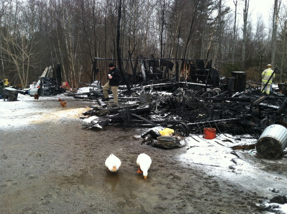 An investigator with the State Fire Marshal’s Office, left, and acting Fire Chief Harold Stoddard examine the ruins from a fire Monday in North Yarmouth.