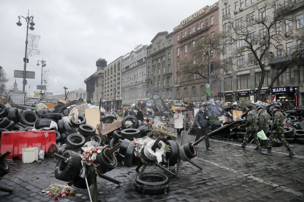 People pass barricades near the Dnipro Hotel in Kiev, where a tense standoff between Ukrainian police and a radical nationalist group Right Sector ended Tuesday when its members surrendered their weapons. Their departure followed a shooting spree in which a Right Sector member shot and wounded three people, including a deputy mayor, outside a restaurant adjacent to the capital’s Independence Square.