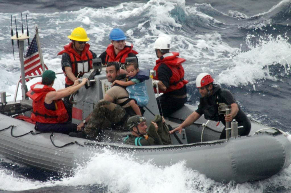 In this photo provided by the U.S. Coast Guard, sailors from Oliver Hazard Perry-class frigate USS Vandegrift assist in the rescue Sunday of a family with a sick infant as part of a joint U.S. Navy, Coast Guard and California Air National Guard rescue effort.