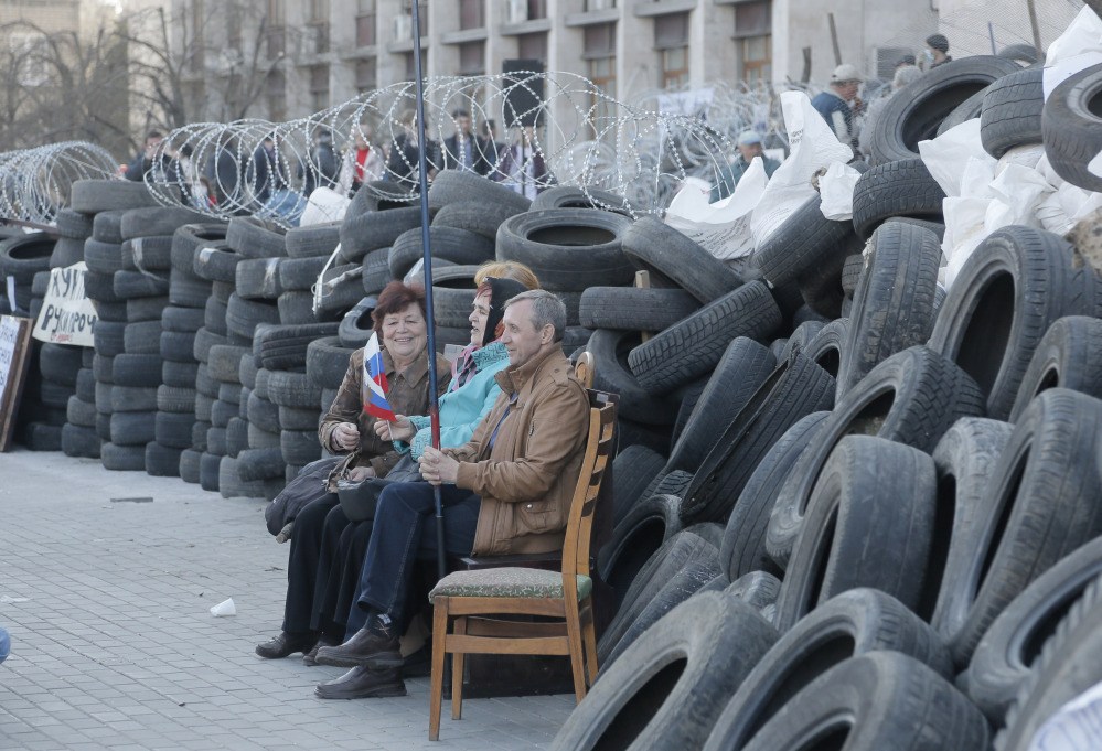 Pro-Russian activists with Russian flag sitting at a barricade at the regional administration building in Donetsk, Ukraine, Tuesday, as the makings of a self-appointed government began to take shape, with demonstrators dug in for their third day at the 11-story headquarters.